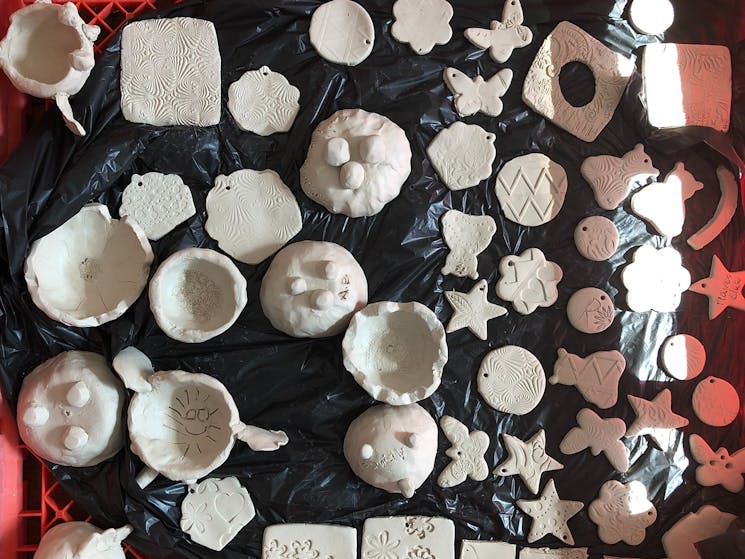 photo shows a large tray filled with pieces of pottery made by children