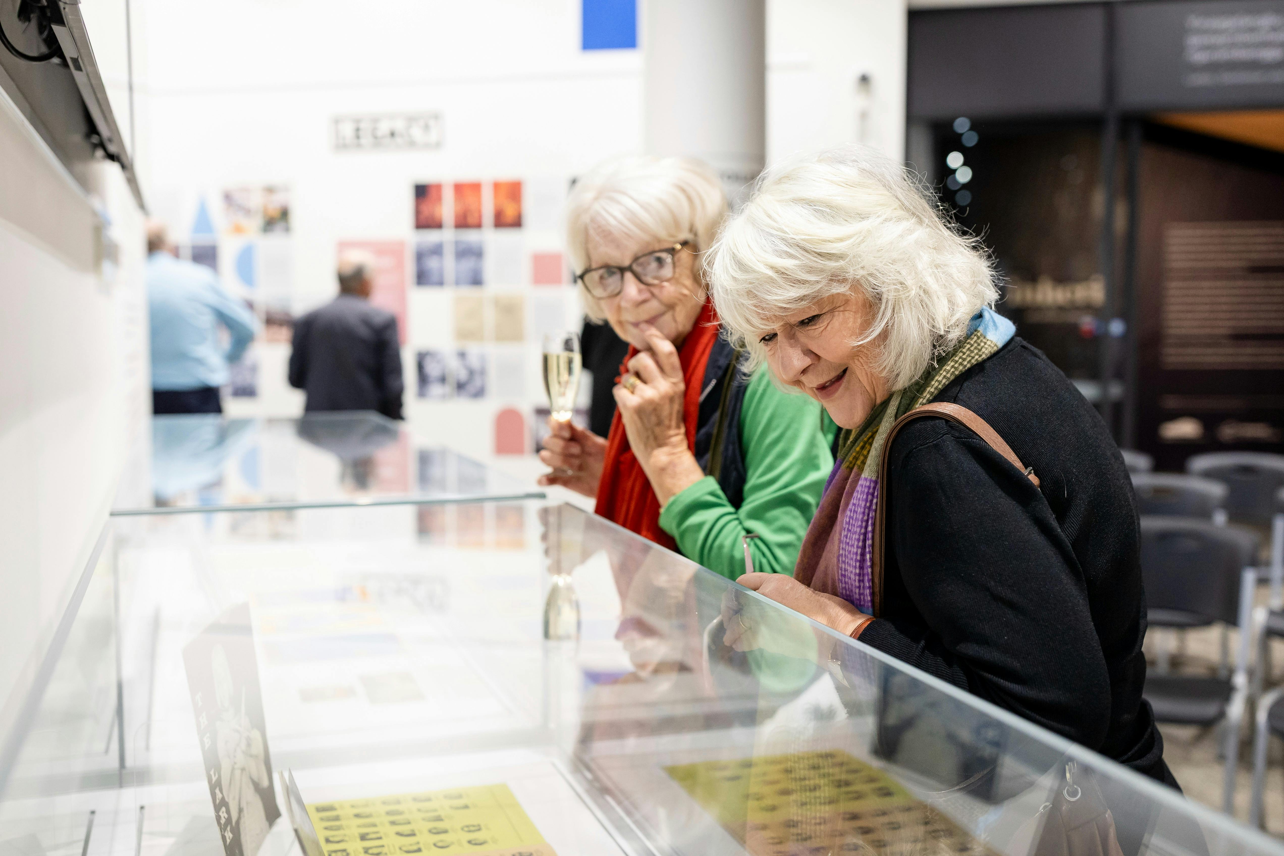 Visitors look at objects in the 'ASSEMBLE: Orange Festival of Arts 1965-1987' exhibition