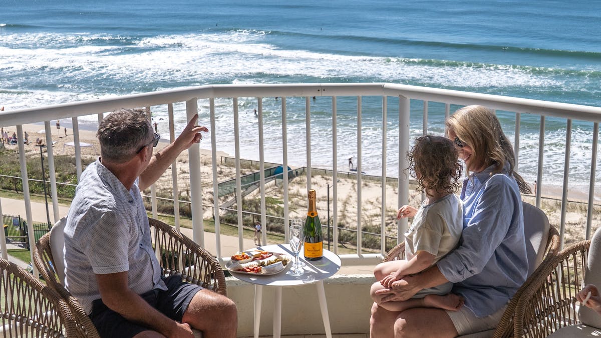 Family sitting on balcony overlooking the ocean