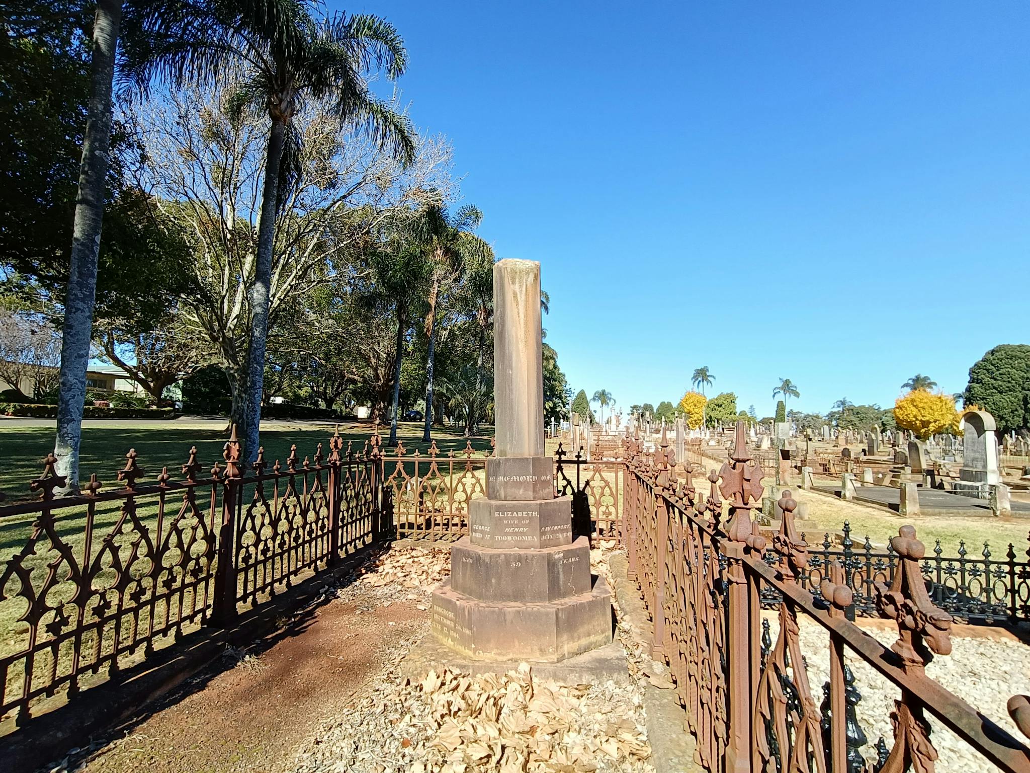 A large family plot with a wrought iron fence  and a large monument with a broken column