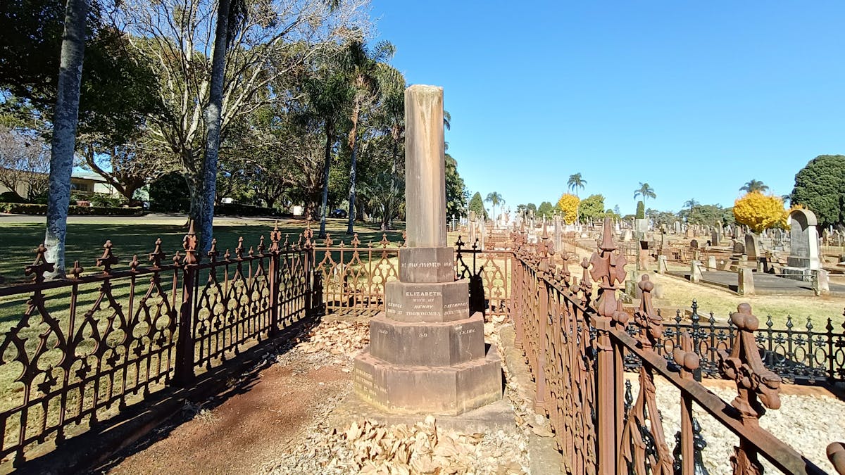 A large family plot with a wrought iron fence  and a large monument with a broken column