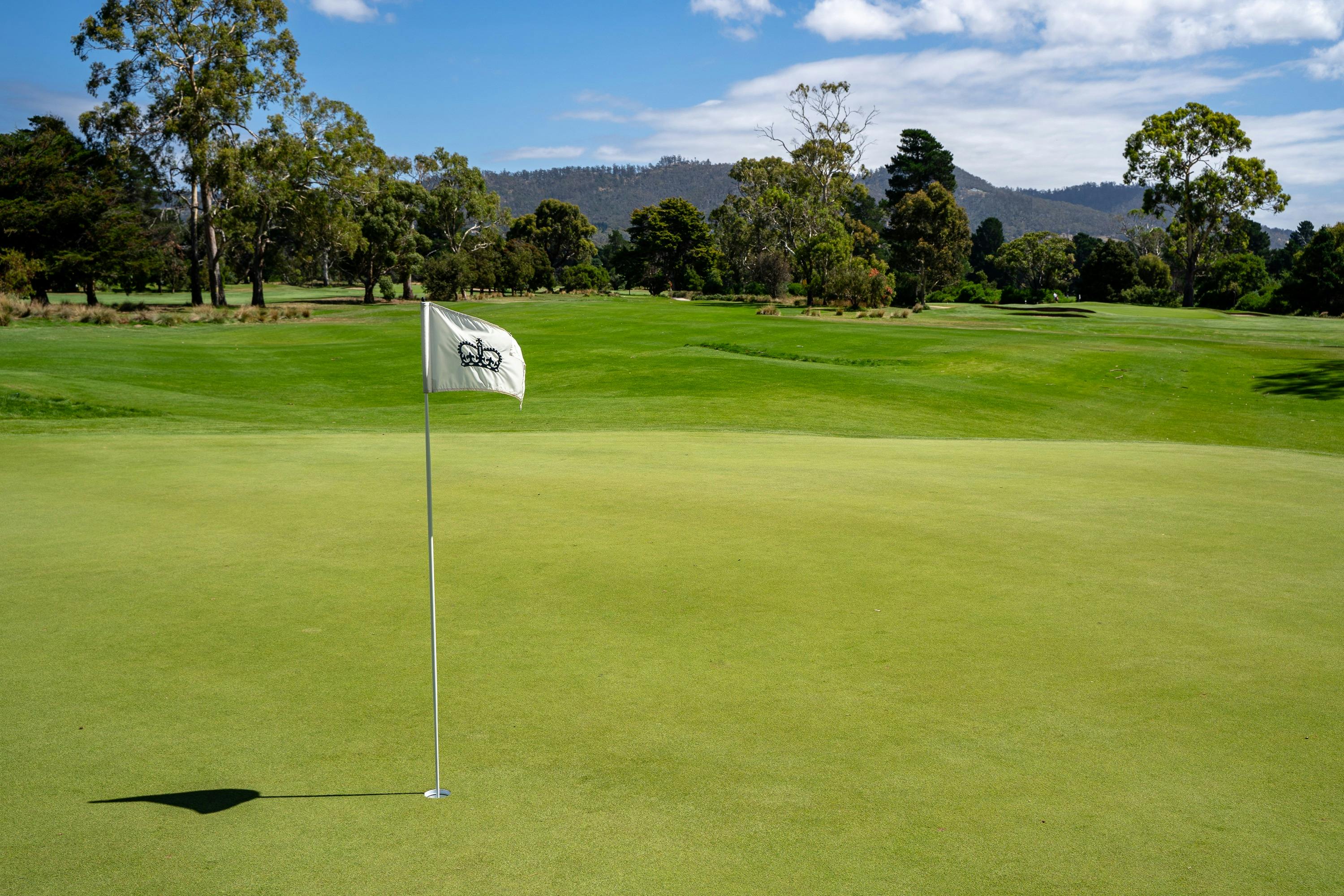 Golf green looking back down fairway, white flag and flagstick in foreground
