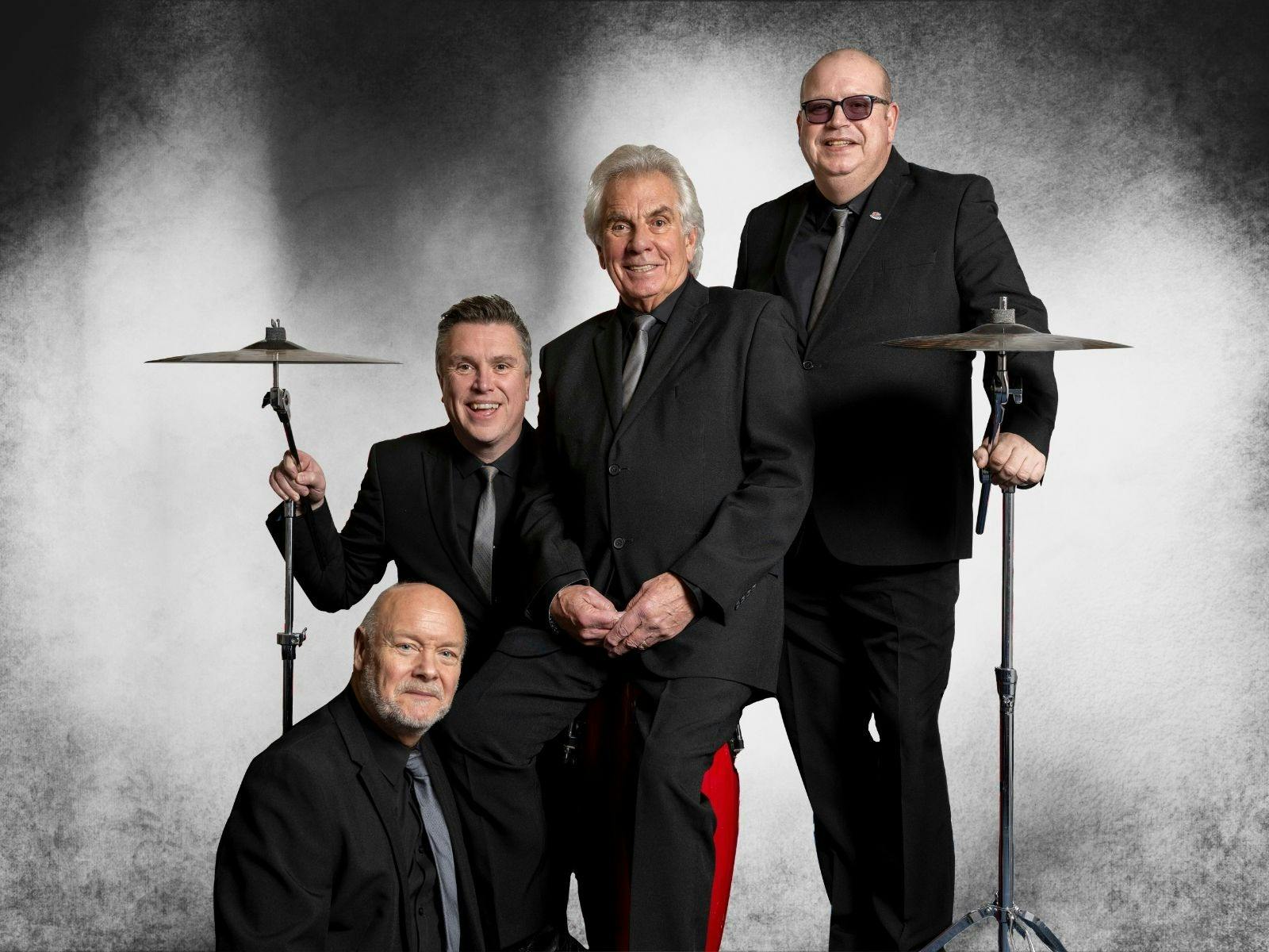 4 men in dark suits with drum symbols on each end 4 men in dark suits with drum symbols on each end