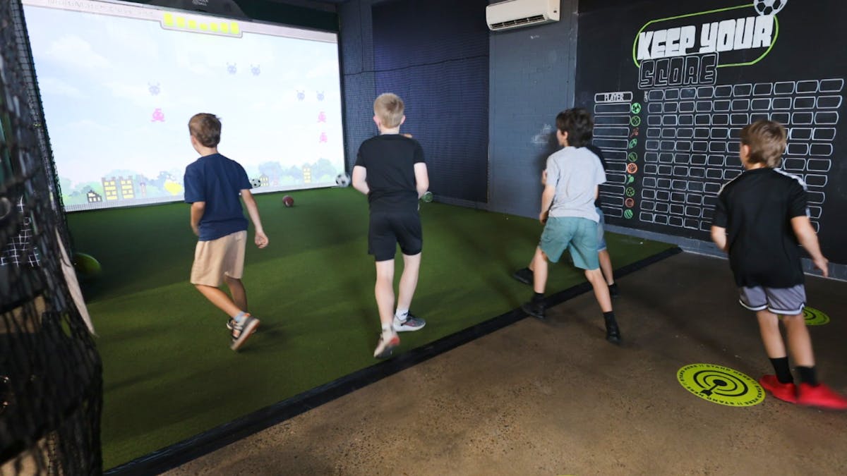 Teenage boys group session at MultiMatch Cleveland playing interactive sports games indoors.