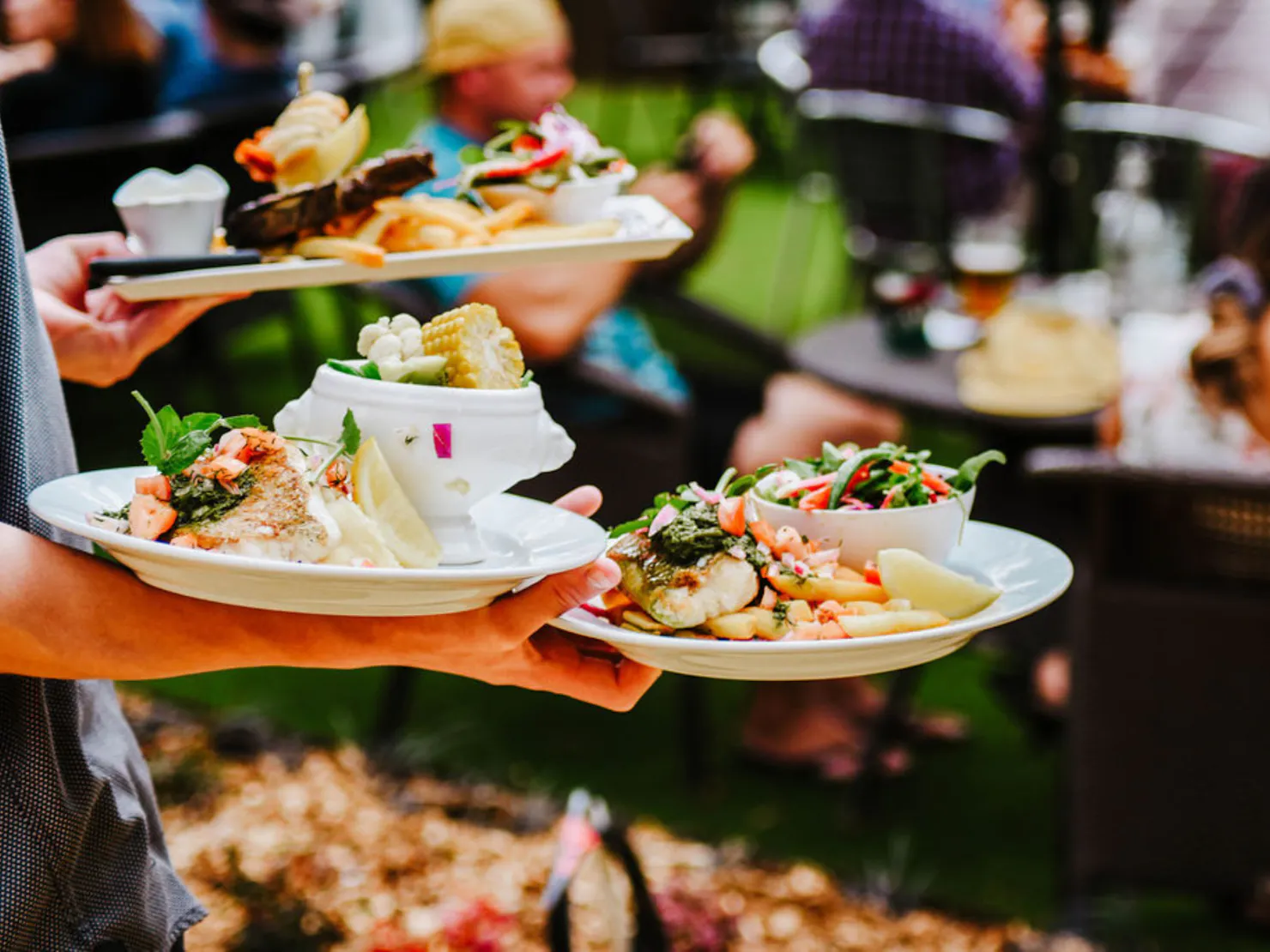 Person carrying multiple plates with food on them in the Maleny Hotel beer garden