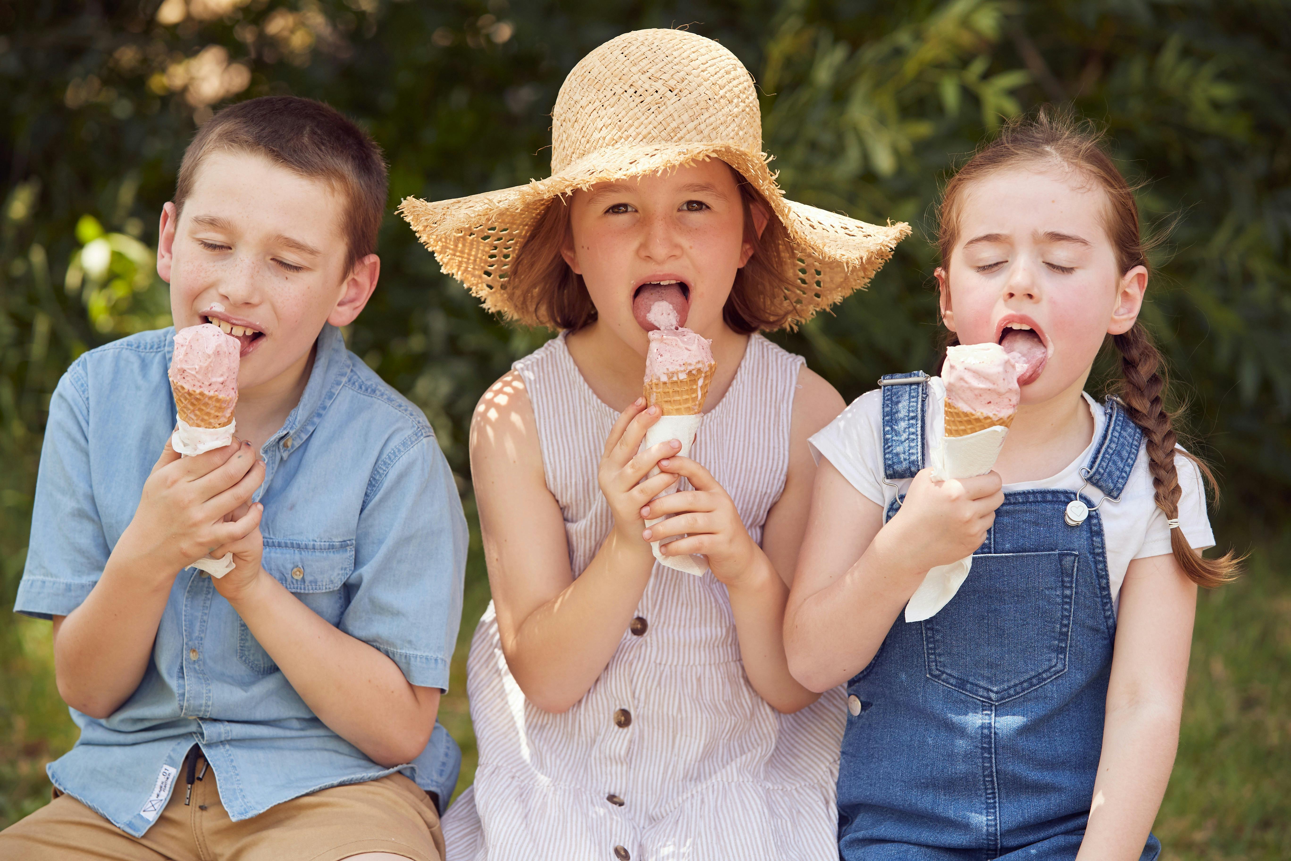 Three children enjoying strawberry ice creams