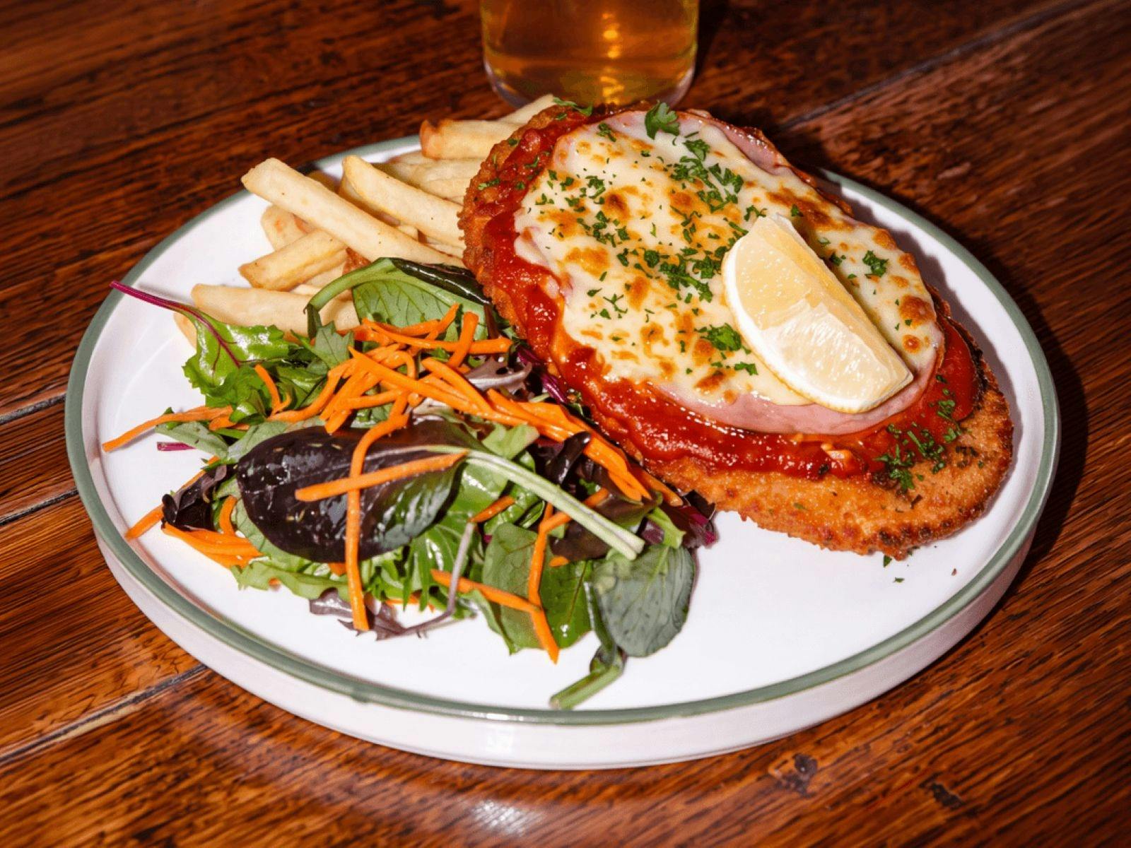 Chicken parmi on a plate with chips and salad.