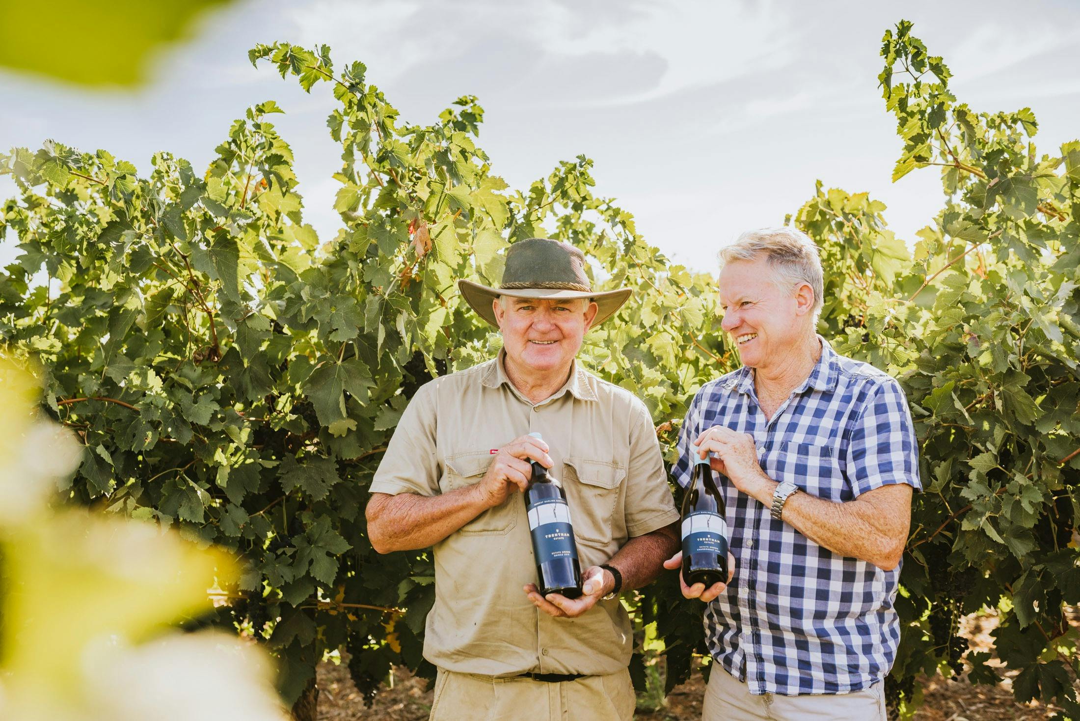 Anthony and Pat Murphy posing in the Estate's grapevines, holding bottles of Trentham Estate wine