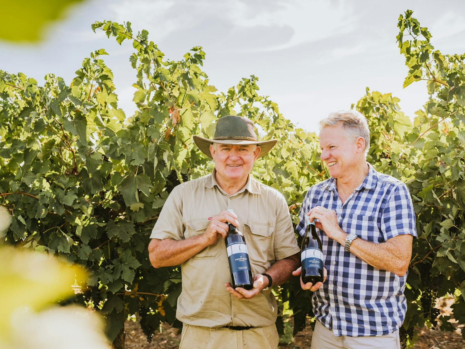 Anthony and Pat Murphy posing in the Estate's grapevines, holding bottles of Trentham Estate wine