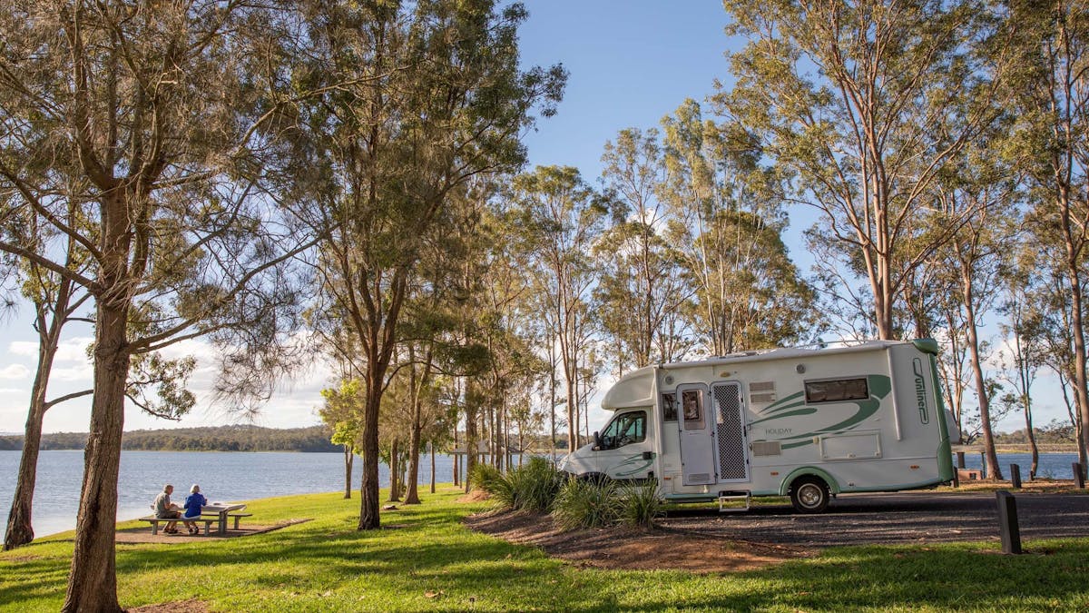 A couple having a picnic beside Lake Samsonvale, with their Campervan parked at Bullocky Rest