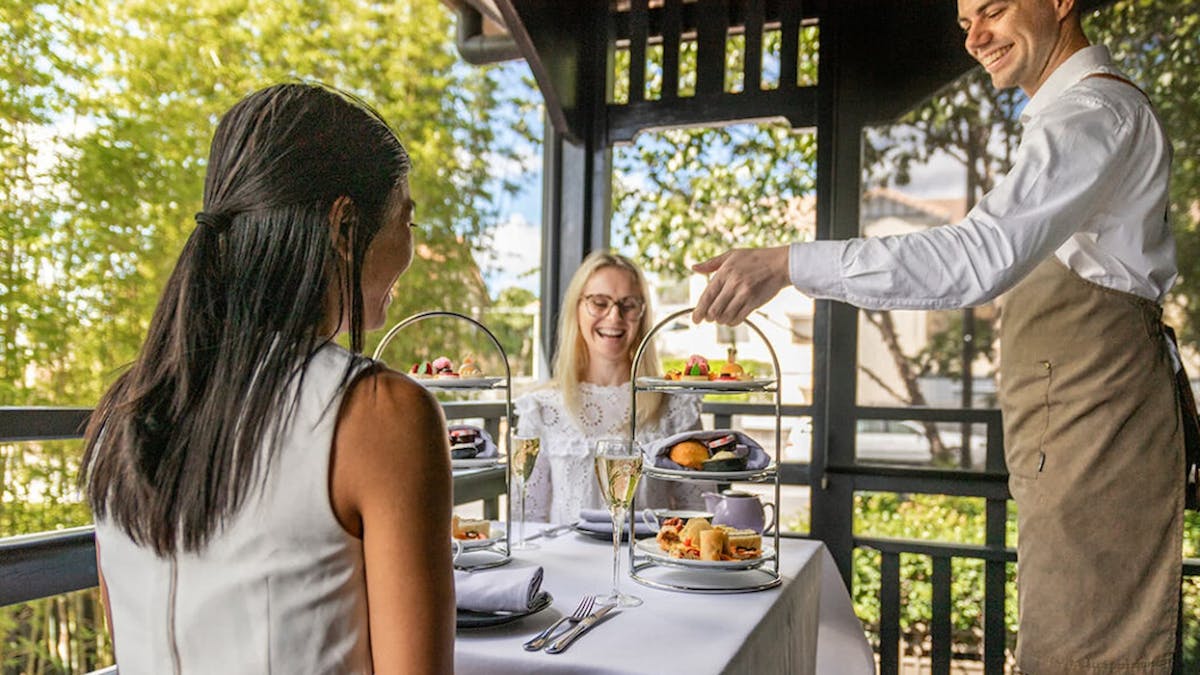 Two high tea stands with sweet and savoury treats being served on a table