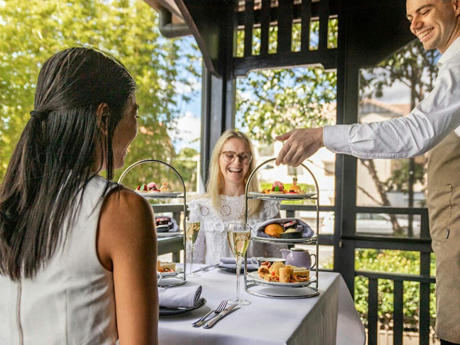 Two high tea stands with sweet and savoury treats being served on a table Two high tea stands with sweet and savoury treats being served on a table