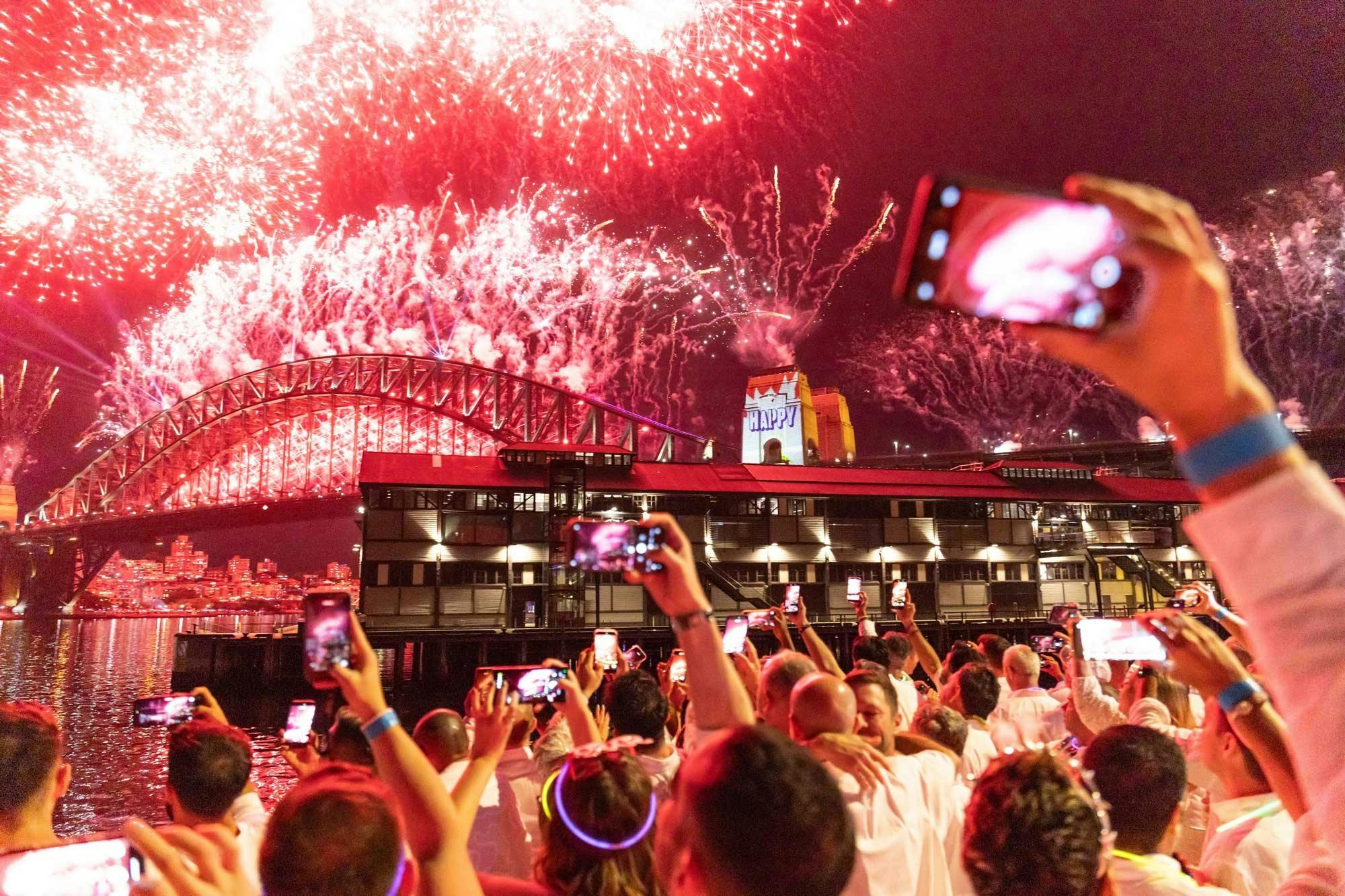 Crowd watching fireworks over Sydney Harbour Bridge.
