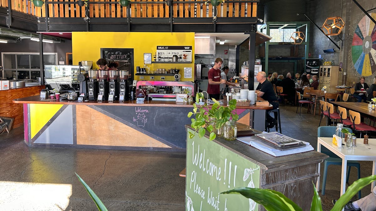 Image shows front counter with coffee machine and Maitre'd desk with welcome sign.