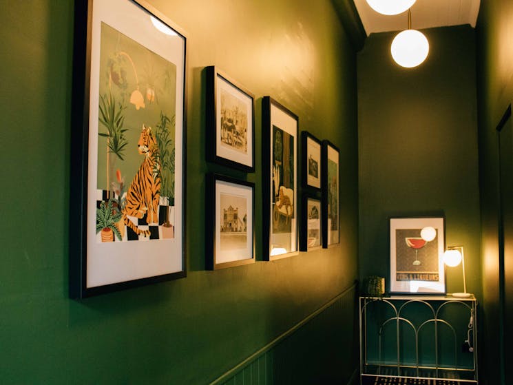 A bold green hallway with modern art deco prints and historic photos.