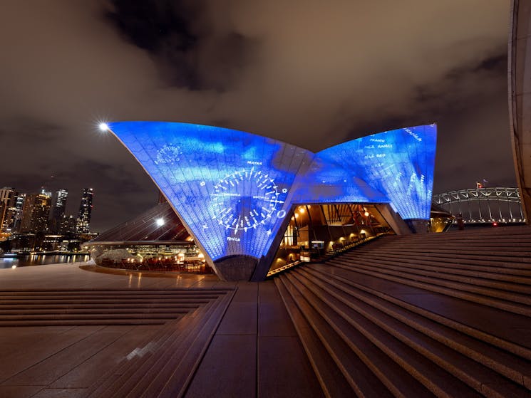 Bennelong sails illuminated with white outline of compasses on a blue background
