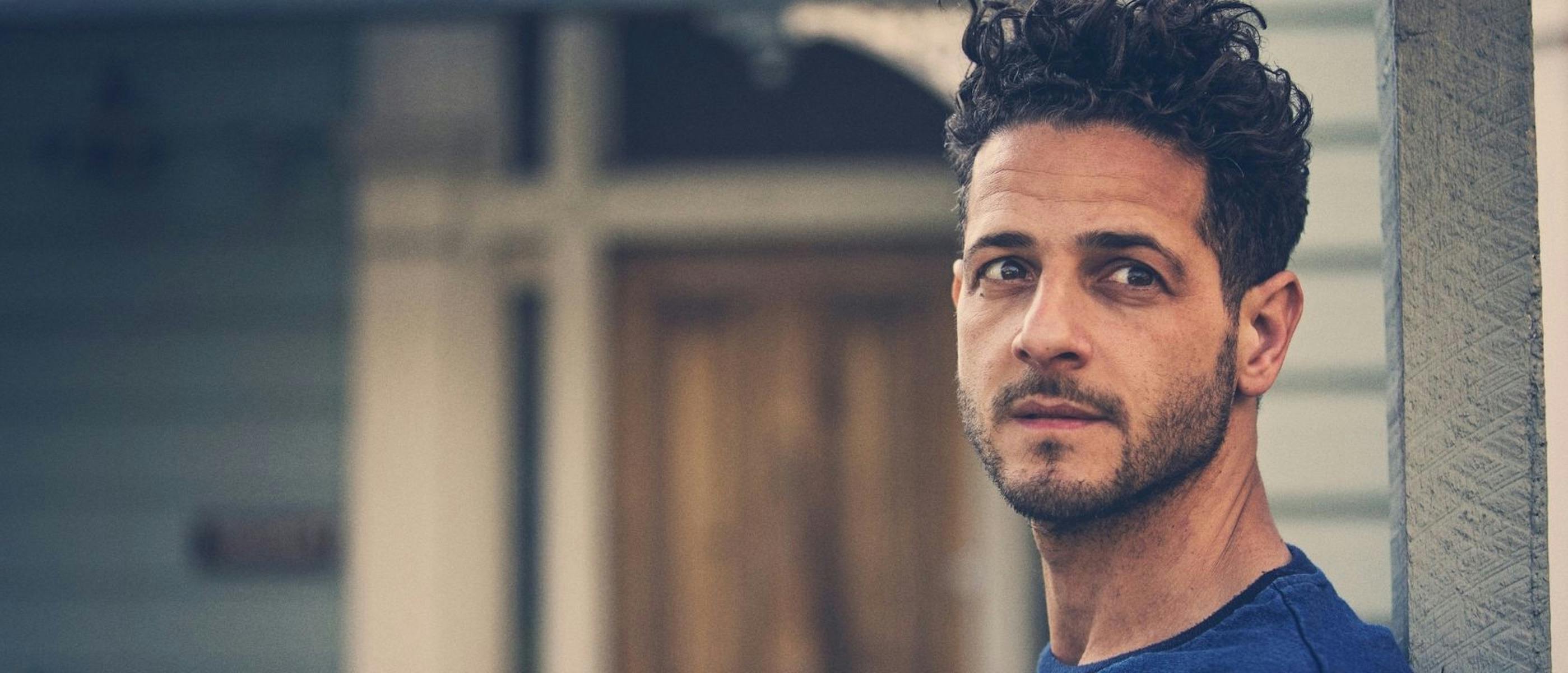 Man wearing a blue top looks into the distance