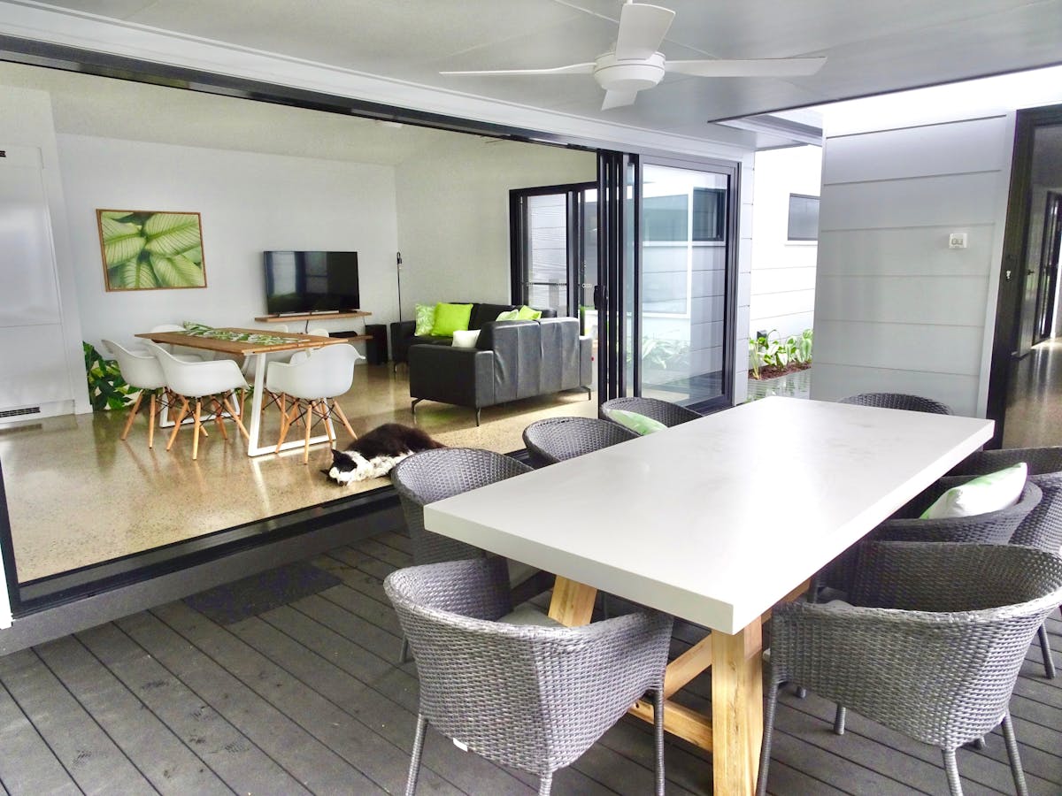 Indoor living and dining area opens out onto the covered patio with outdoor dining table and bbq