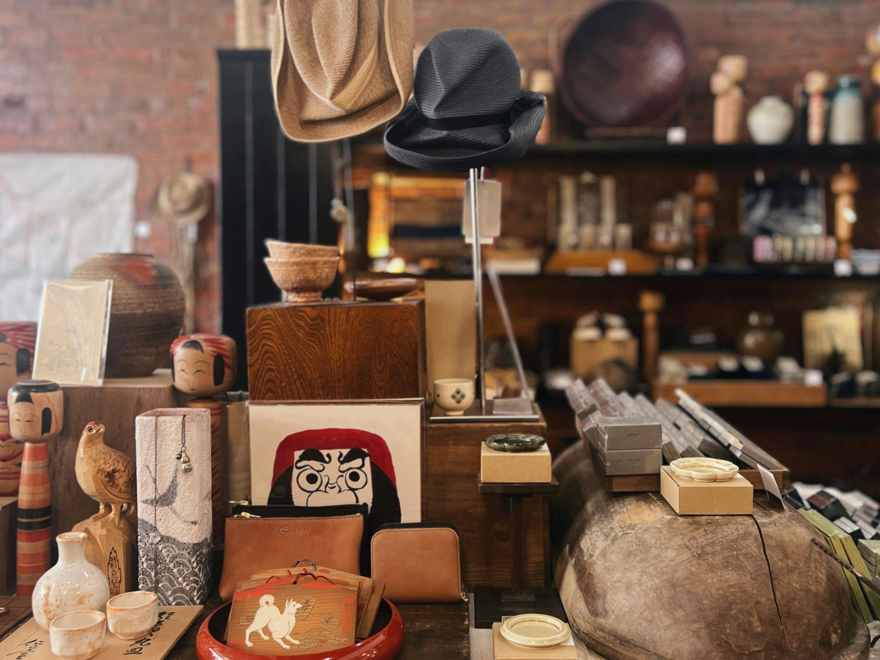A central table in the store is crowded with Japanese vintage pieces, contemporary hats, and kokeshi