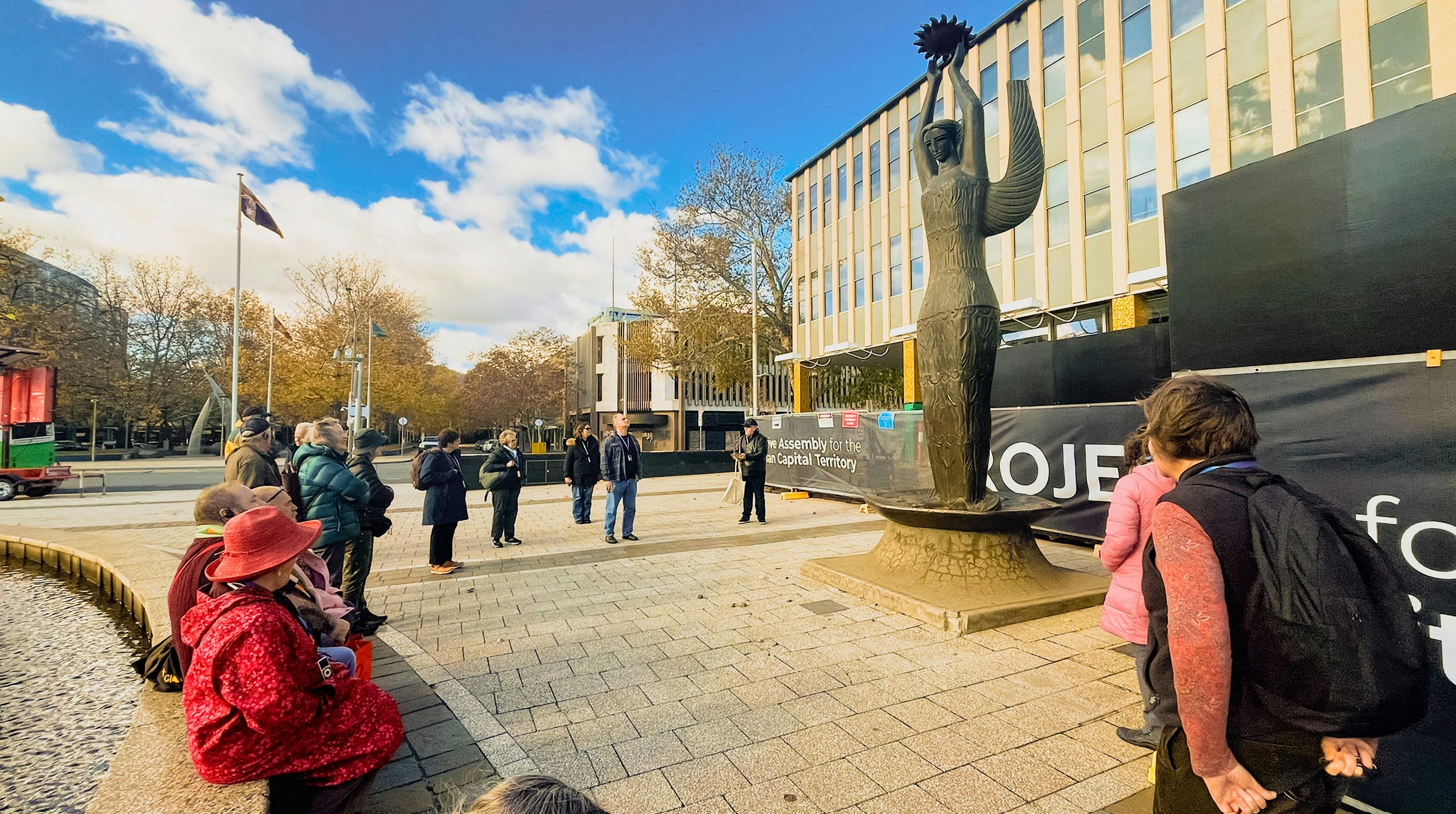 A walking tour group stands in front of the Ethos sculpture at ACT Legislative Assembly