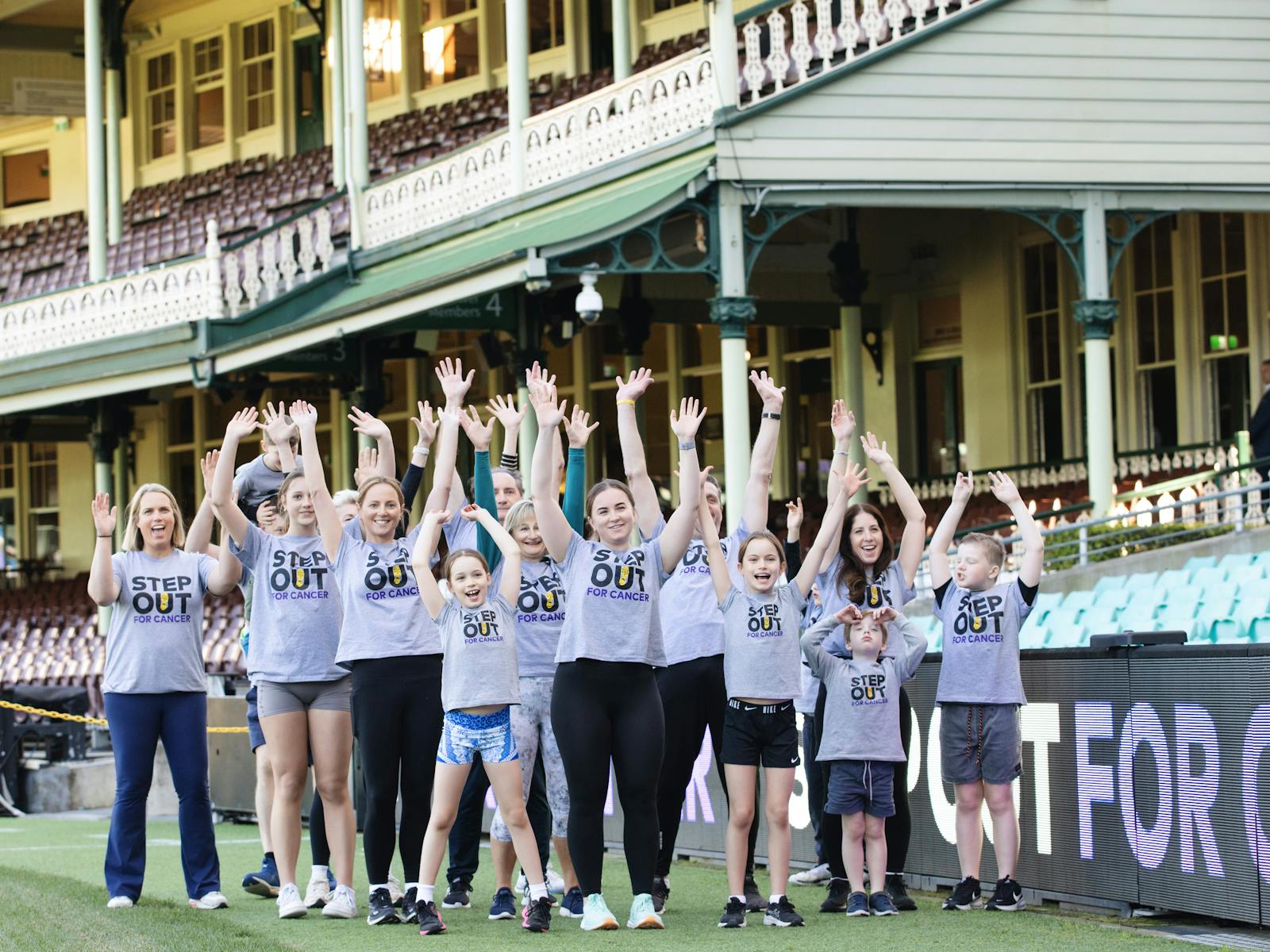 People all ages standing on the Sydney Cricket Group celebrating at Step Out for Cancer event