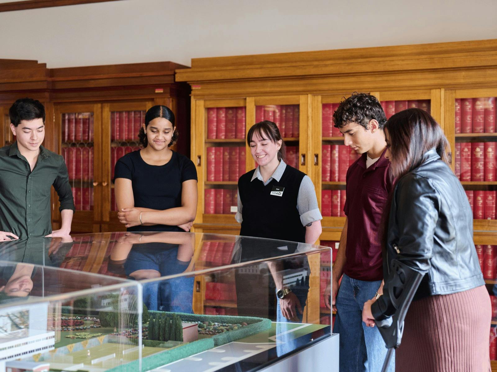 A group of people view a miniature version of Old Parliament House beneath a glass display cabinet