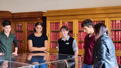 A group of people view a miniature version of Old Parliament House beneath a glass display cabinet