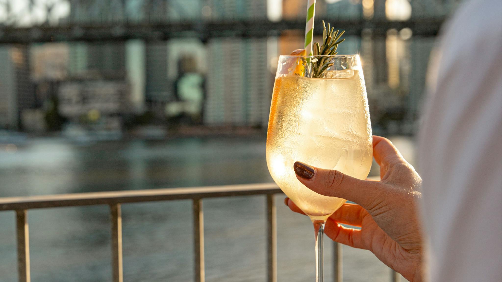 Hand holding cocktail overlooking the river