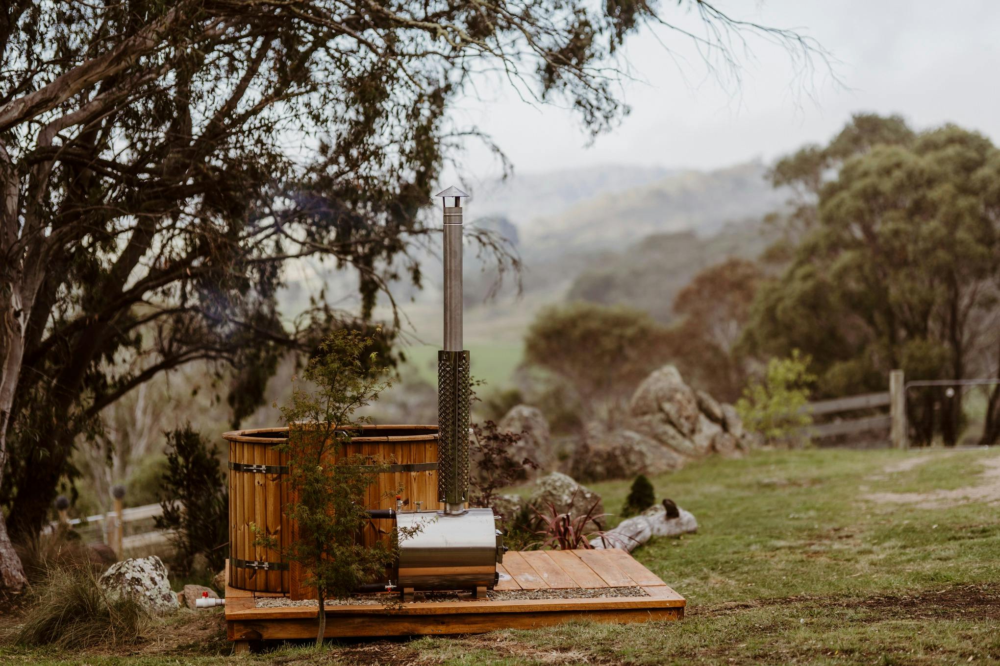The wood fired hot tub is getting ready to be used. Amazing view of rolling hills behind it.