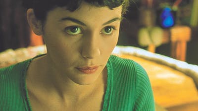 Woman with dark hair and green top looks up at the camera