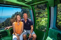 Two people sitting in Skyrail Rainforest Cableway gondola, enjoying scenic views.