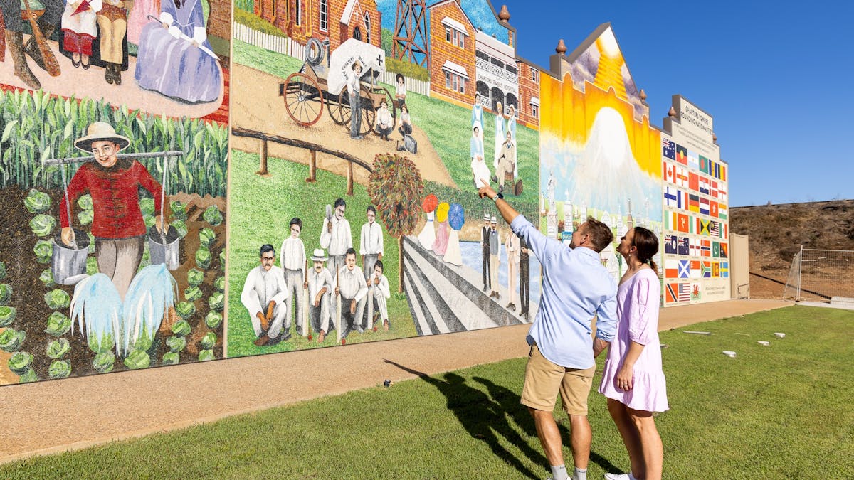 Couple looking and pointing at Charters Towers Wall of History 1872-1922