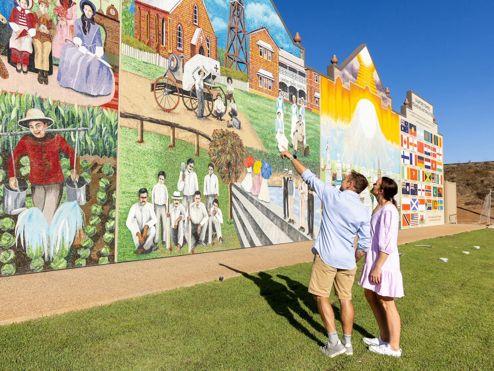 Couple looking and pointing at Charters Towers Wall of History 1872-1922