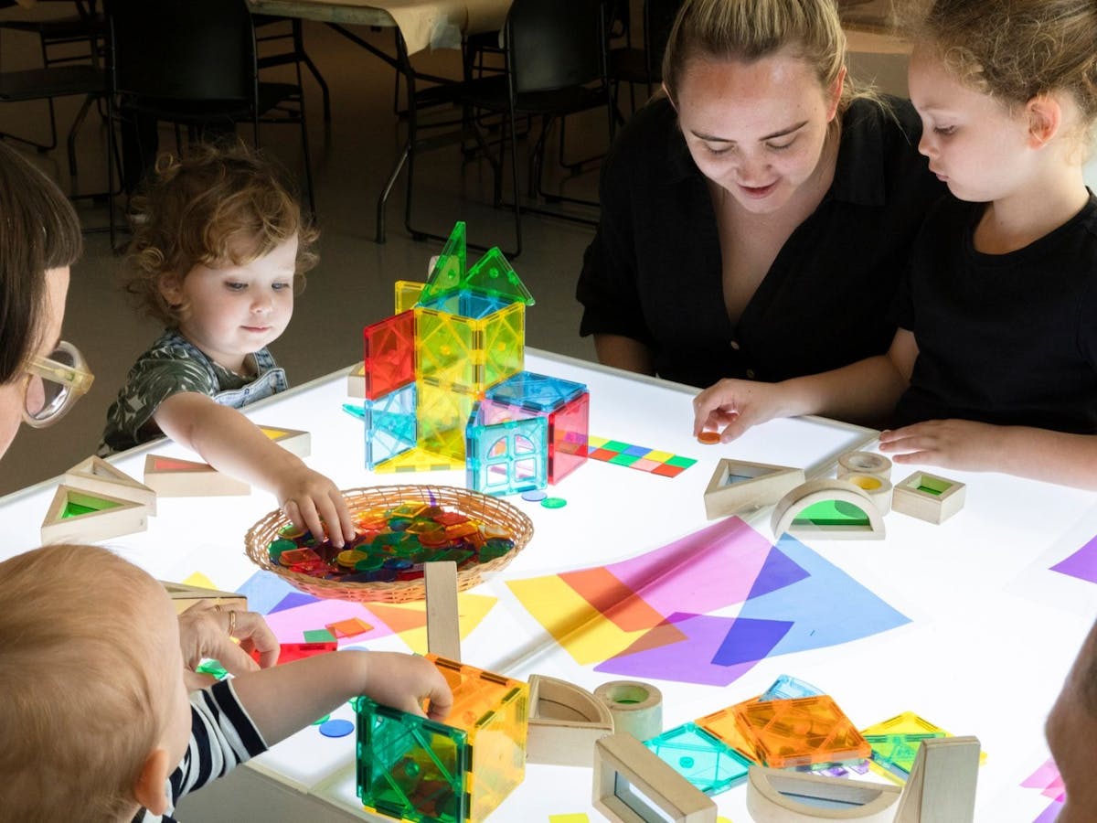 Toddlers, young children and their families engage in art activities with colourful paper