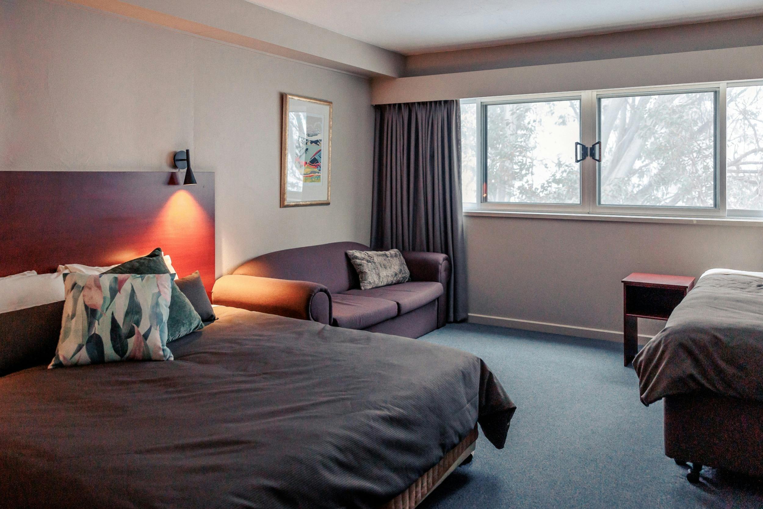 Four share room showing the view, king bed, sofa and single bed