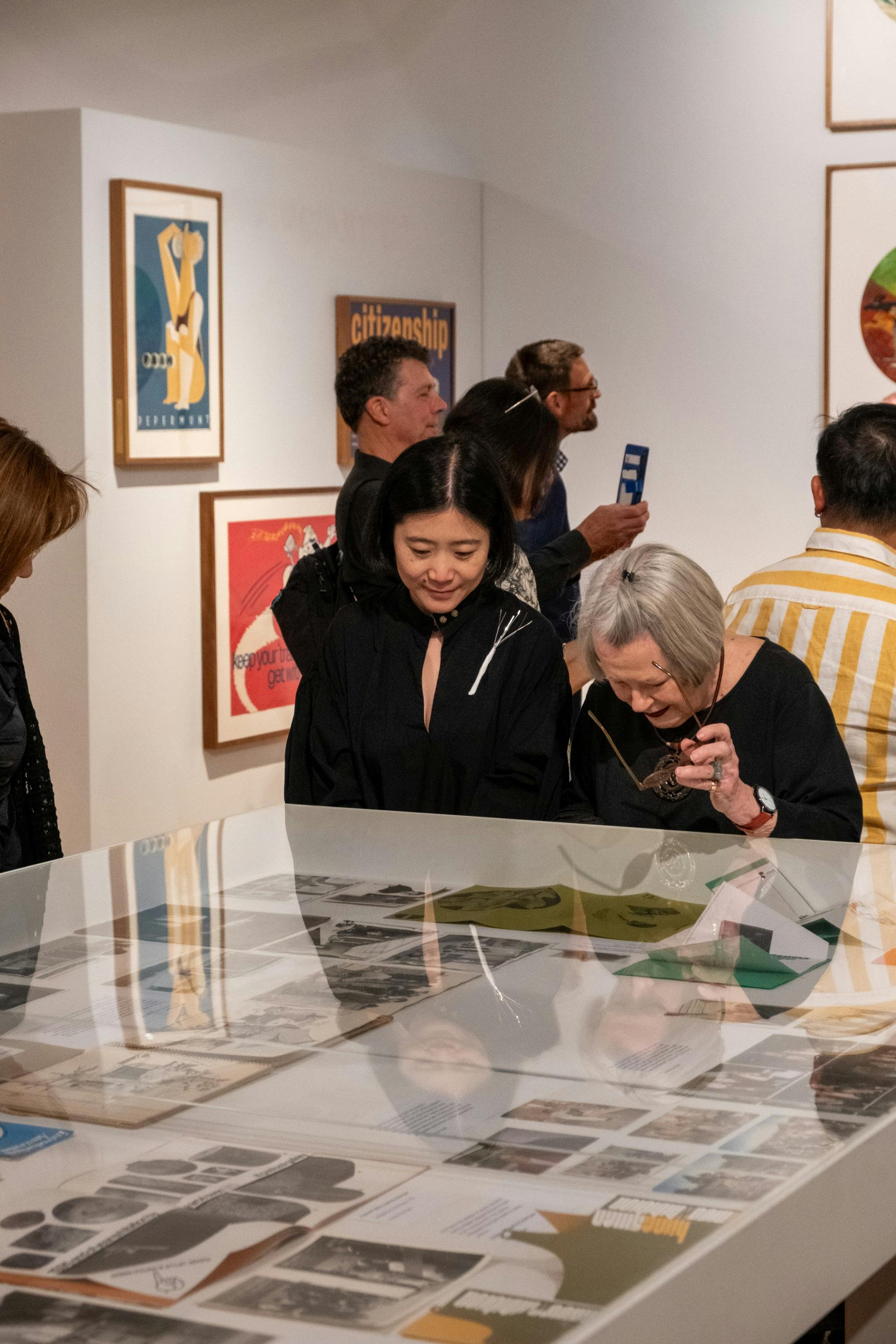 Two women observing objects relating to Cornel & Hiroe Swen's life at Canberra Museum + Gallery