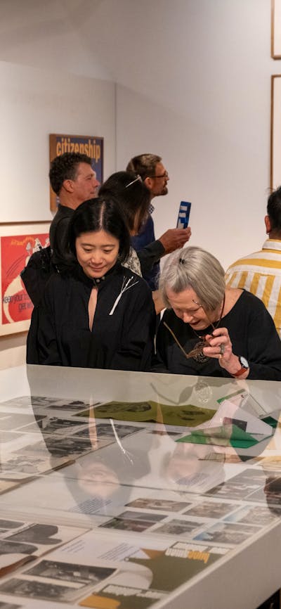 Two women observing objects relating to Cornel & Hiroe Swen's life at Canberra Museum + Gallery