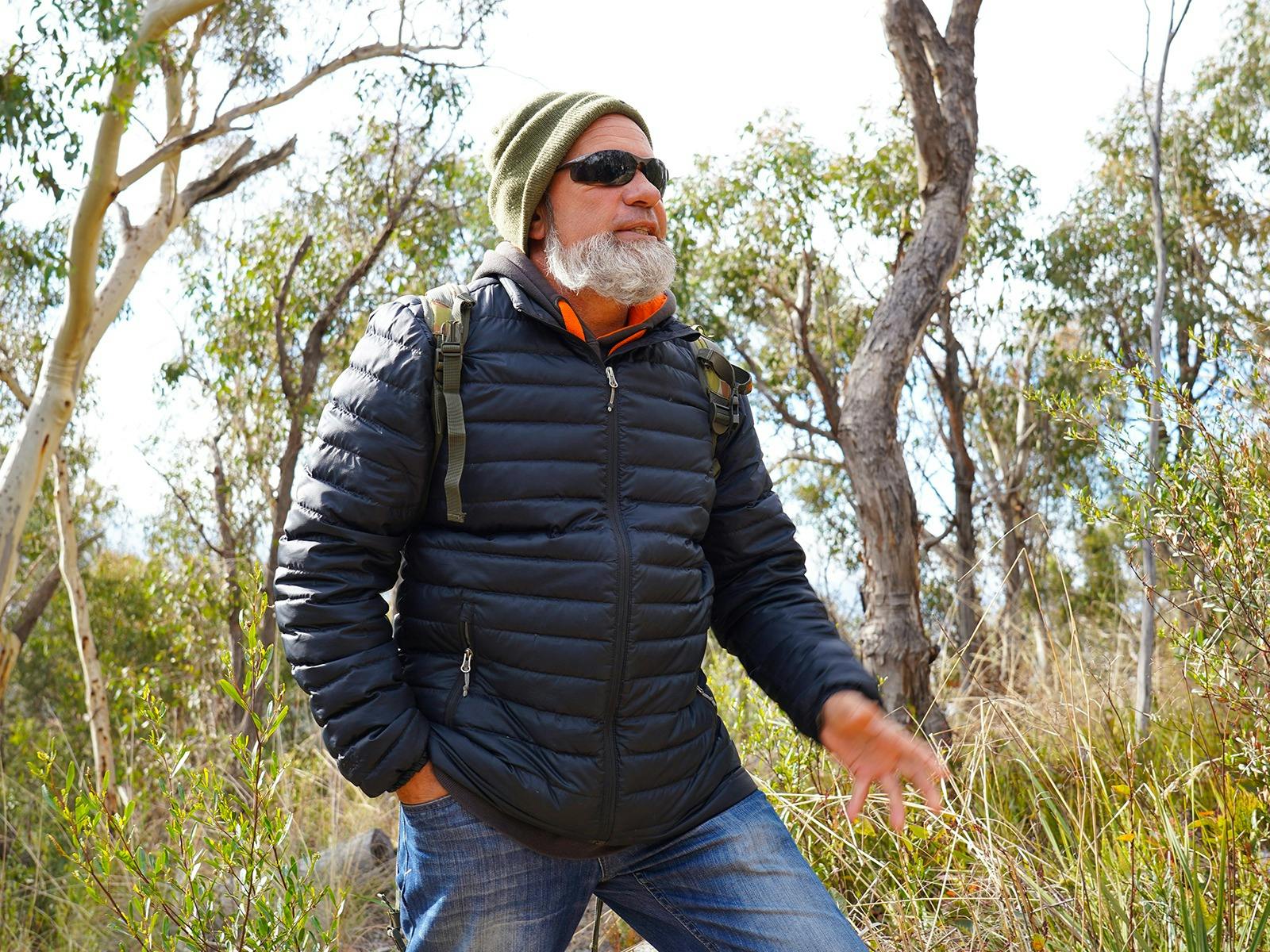 First Nations man Tyronne Bell stands in a heavily grassed eucalyptus forest