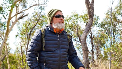 First Nations man Tyronne Bell stands in a heavily grassed eucalyptus forest