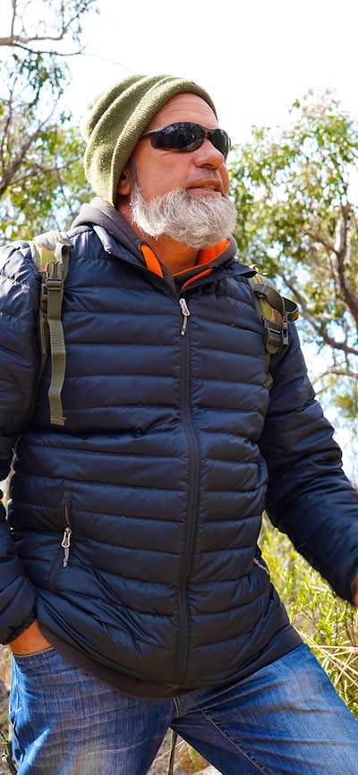 First Nations man Tyronne Bell stands in a heavily grassed eucalyptus forest
