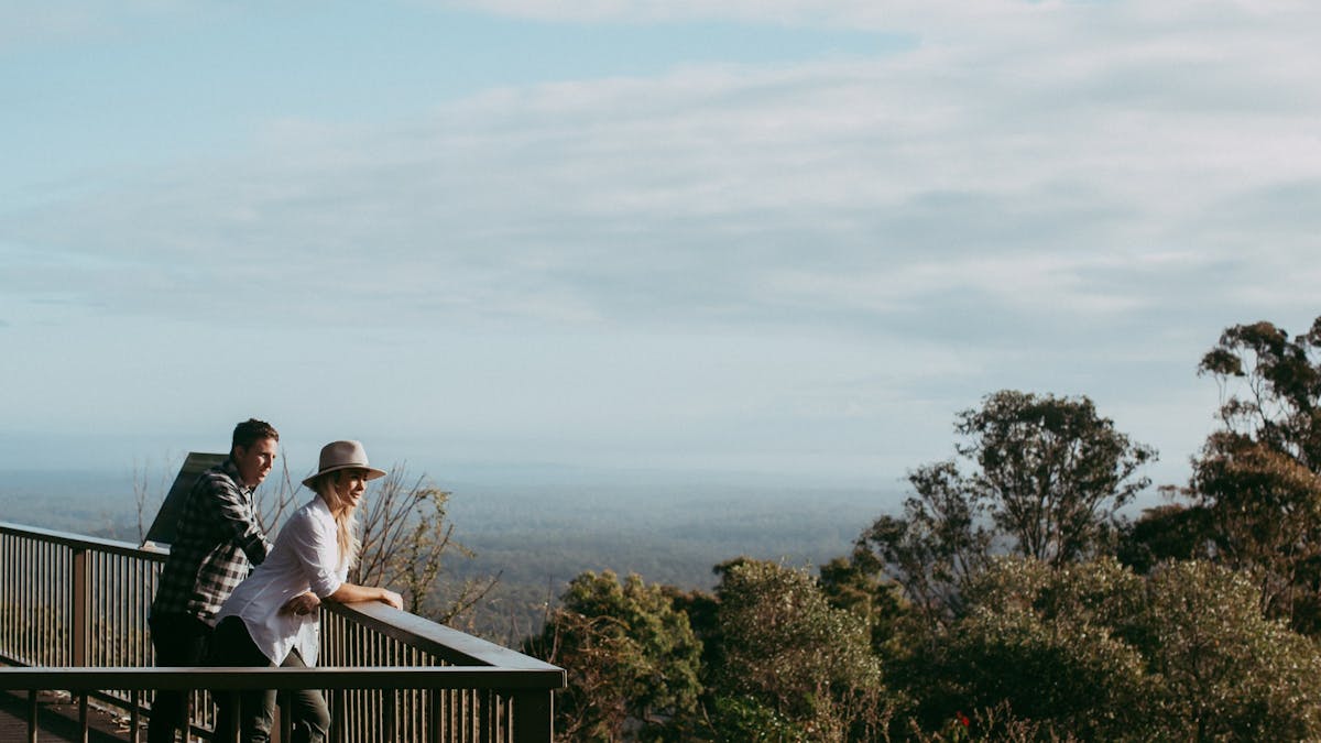 Man and woman smiling as they admire wide coastal views from the escarpment