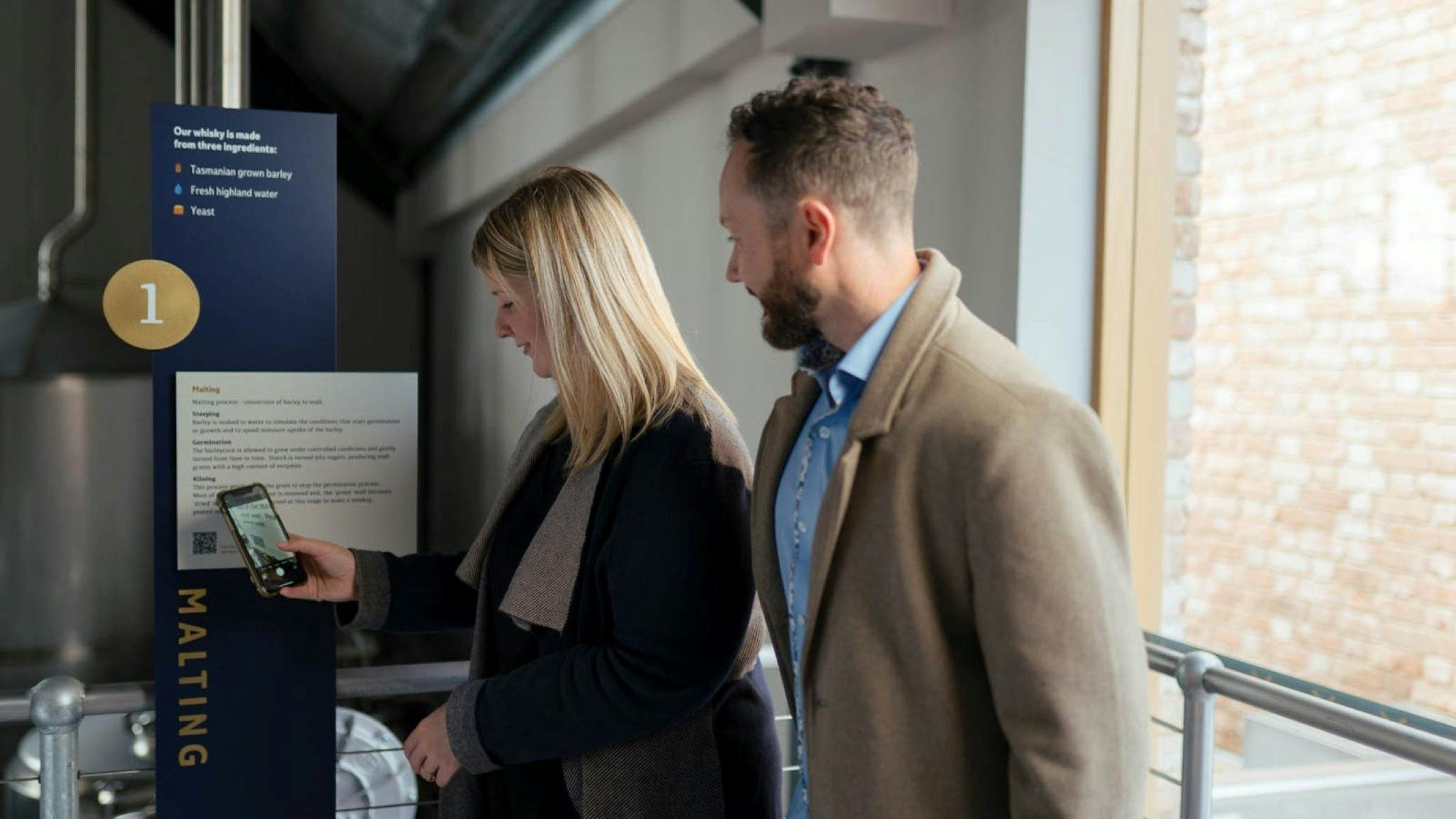 A man and woman scanning a QR code at an interactive station