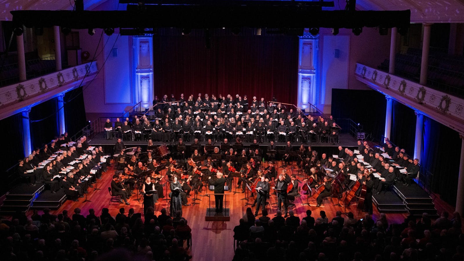Grand performance of Handel's work by a choir and orchestra in a large hall.
