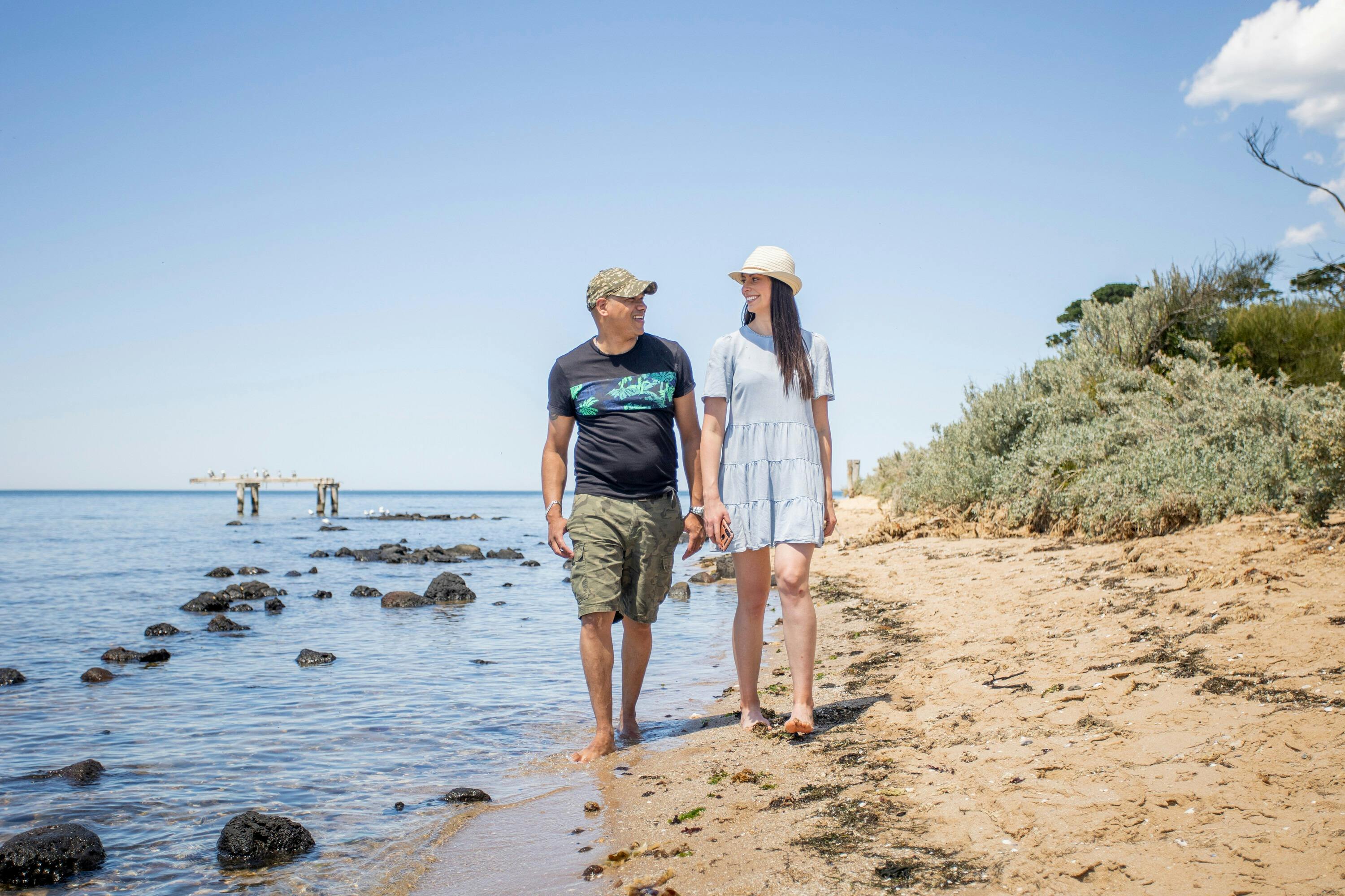 two adults walking barefoot along the beach