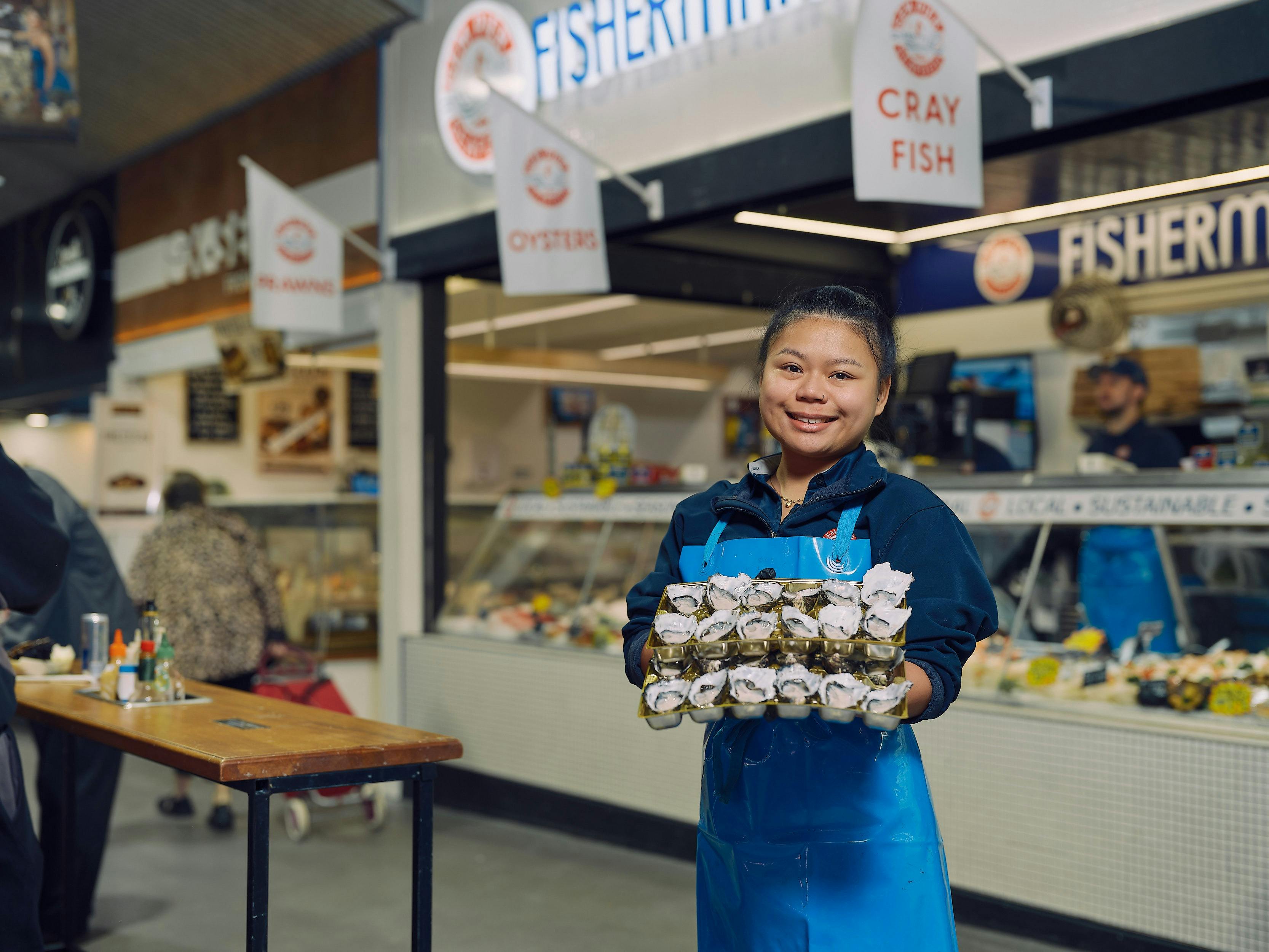 Seafood trader holding a tray of freshly shucked oysters at South Melbourne Market.