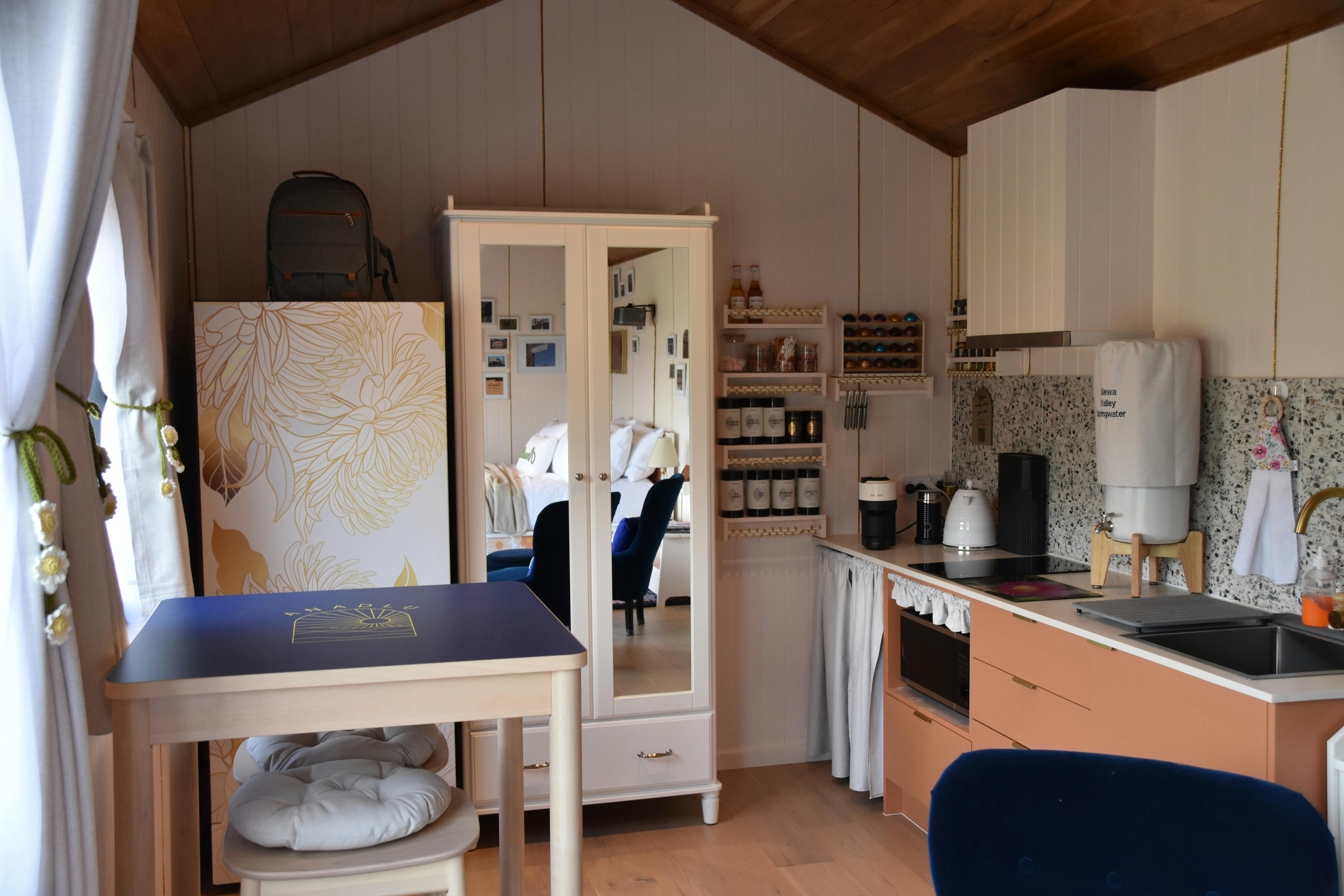 Compact kitchenette in Anwen with cooktop, sink, shelves, tea, coffee and condiments