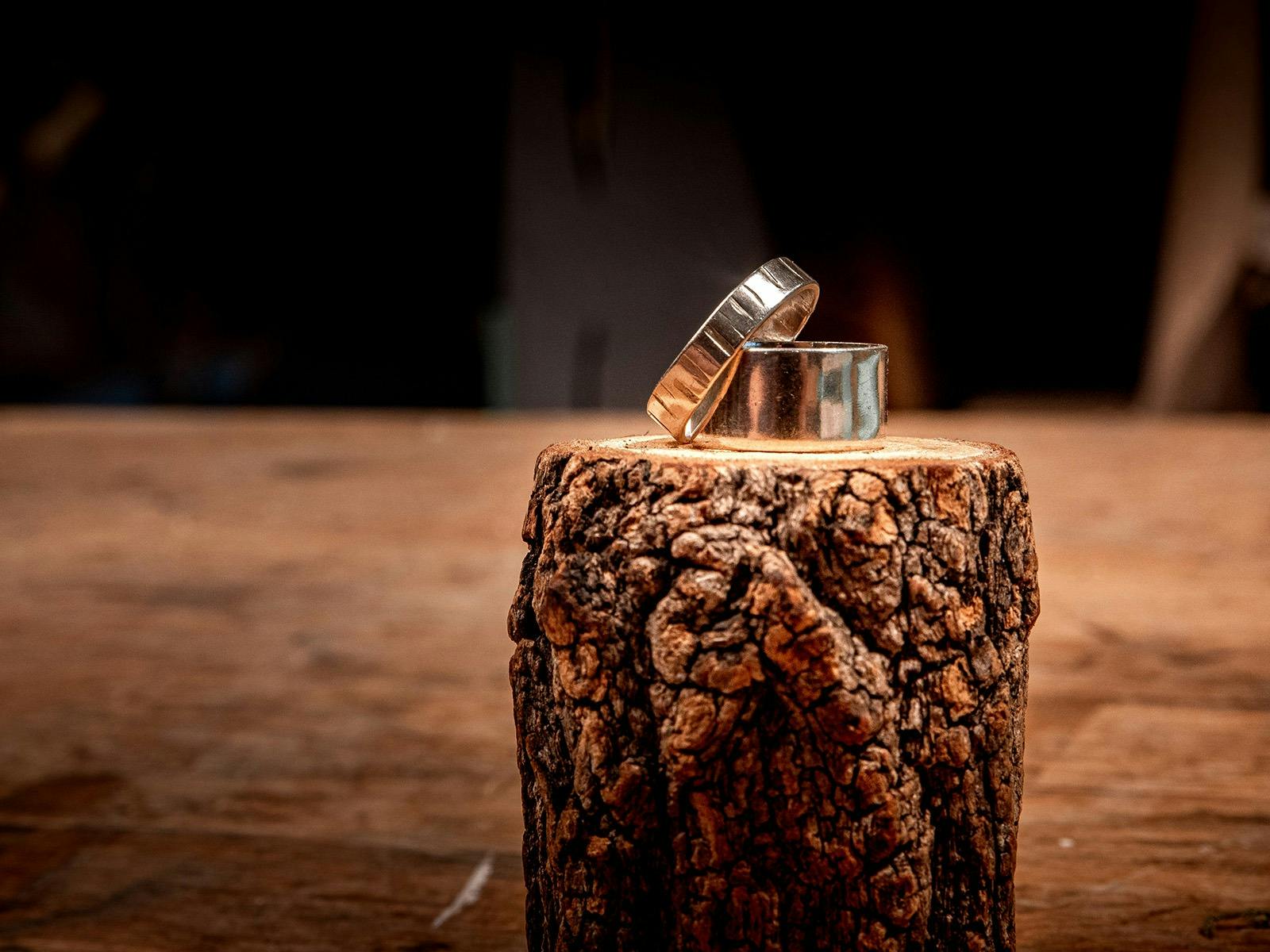 2 silver rings, one large and the other grooved, displayed on log.
