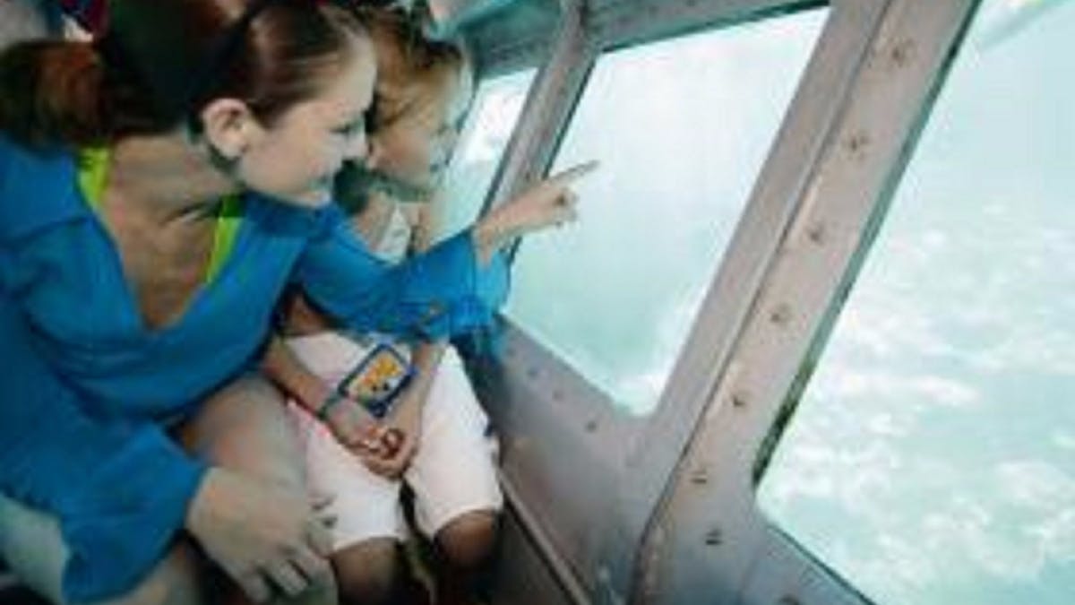 Mom and a daughter smiling and looking out of a semi submersible under water