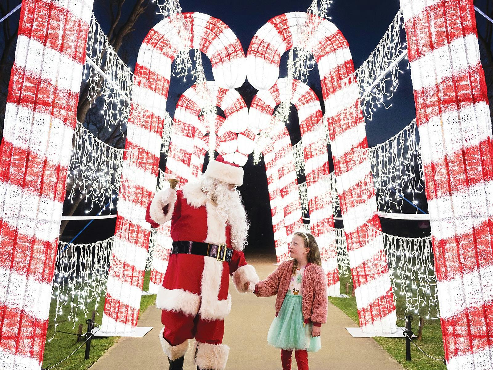 Santa and a girl under a candy cane tunnel