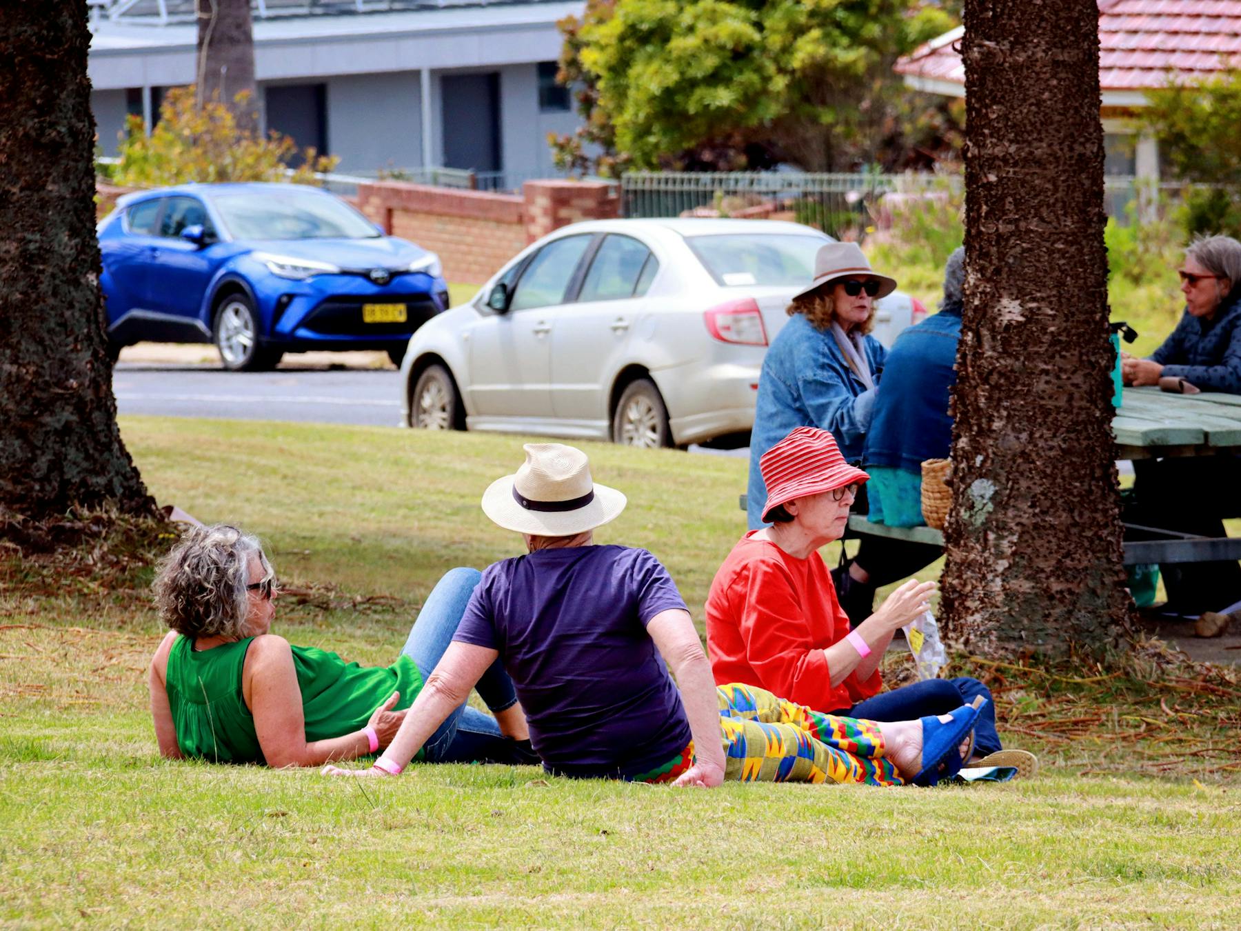 Audience in birghtly coloured clothes relaxing on the grass at Headland